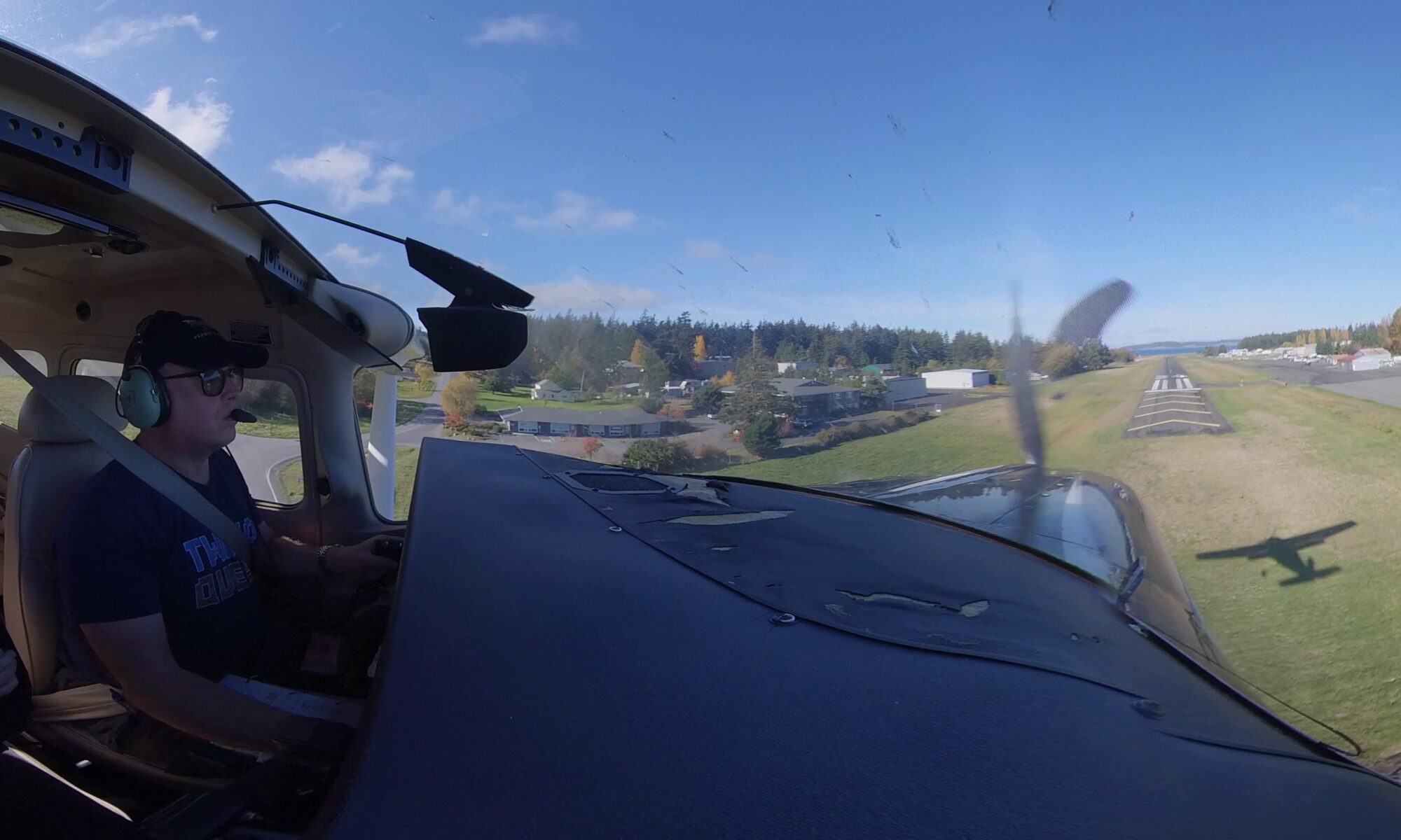 Bob Watson piloting a light plane on a sunny day as it approaches the runway to land