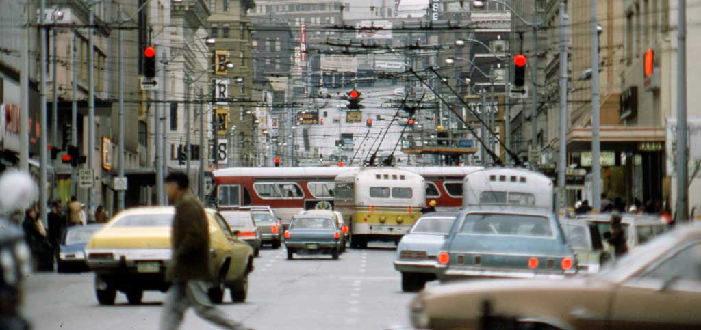 A compressed view of traffic in downtown Seattle with cars, buses, and pedestrians from 1975